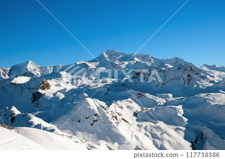 Beautiful view of a large snowy mountain range with blue sky 117738386
