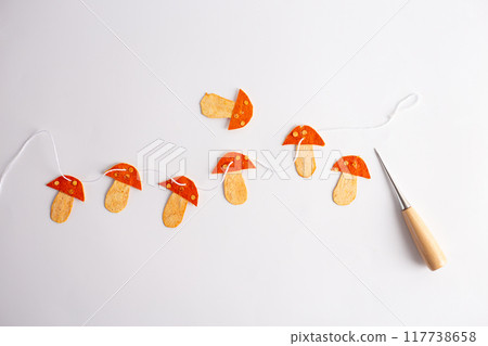 a string of orange mushrooms made of dried tangerine peel sitting on top of a white surface, folk art, DIY 117738658