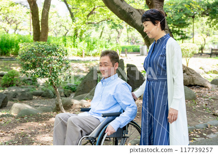 Senior couple walking in the park in wheelchairs 117739257