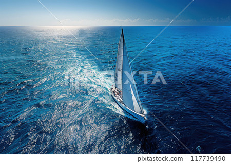 Sailboat gliding through open ocean with clear skies and calm waters creating a peaceful and serene setting and evoking feelings of freedom and adventure 117739490