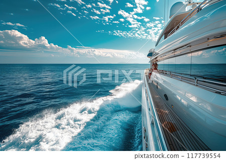 Sailing alongside a luxurious yacht with clear blue waters and partly cloudy sky giving a sense of freedom and adventure on the open ocean 117739554