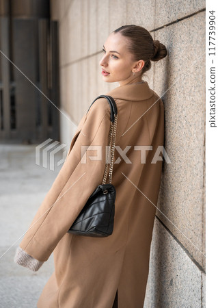 Young beautiful woman wearing coat walking in the city centre of Prague, Europe 117739904