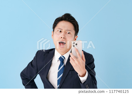 A businessman surprised with a smartphone A businessman surprised with a smartphone 117740125