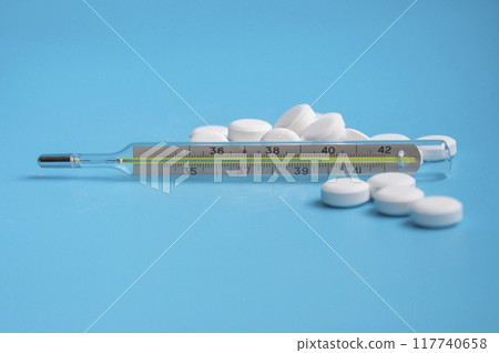 thermometer and white pills on the blue background thermometer and white pills on the blue background 117740658
