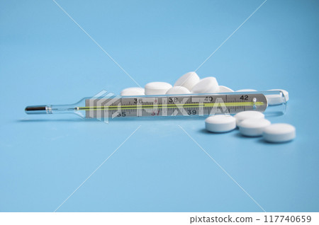 thermometer and white pills on the blue background thermometer and white pills on the blue background 117740659