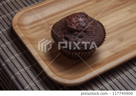Dark chocolate muffin on wooden dish Dark chocolate muffin on wooden dish 117740900