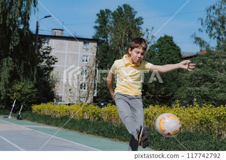 Little caucasian boy kicking soccer ball on playground on summer day 117742792