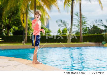 Kids jump into swimming pool. Summer water fun. 117742994