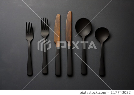 Elegant black cutlery set with wooden accents on dark background 117743022