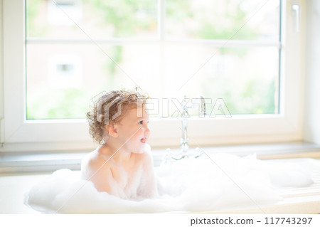 Baby taking bath in kitchen sink 117743297