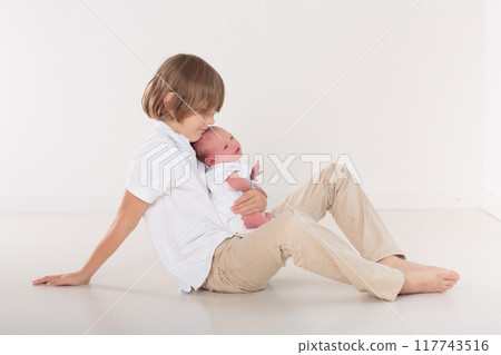 Siblings meet newborn baby 117743516
