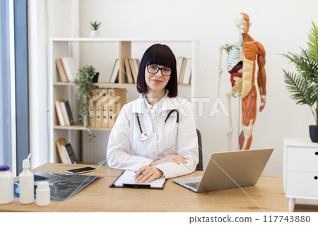 Confident female doctor at office desk ready to assist patients Confident female doctor at office desk ready to assist patients 117743880