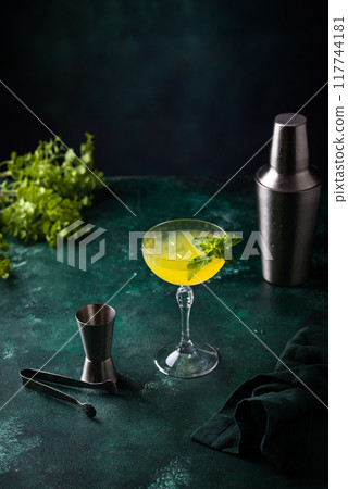 Tropical yellow lemon cocktail on green background Tropical yellow lemon cocktail on green background 117744181