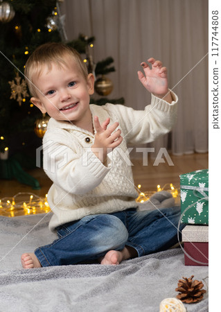 Little two-year-old boy opens Christmas gifts at home 117744808
