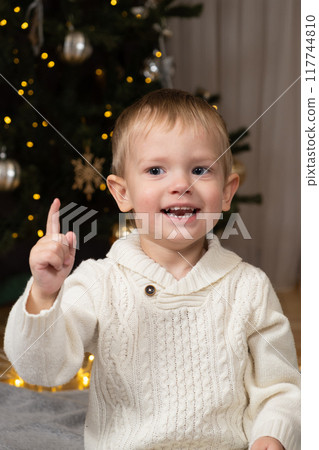 Cute little toddler showing index finger up at christmas pointing at something 117744810