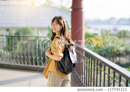 Unveiling the beauty of Bangkok, a smiling Asian woman in her 30s embarks on a solo journey of exploration. Backpack on, camera ready, she captures the essence of urban adventure. Unveiling the beauty of Bangkok, a smiling Asian woman in her 30s embarks on a solo journey of exploration. Backpack on, camera ready, she captures the essence of urban adventure. 117745313