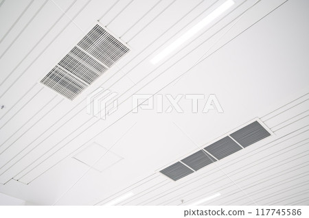 Ceiling mounted cassette type air conditioner and modern lamp light on a white ceiling. duct air conditioner for office or home Ceiling mounted cassette type air conditioner and modern lamp light on a white ceiling. duct air conditioner for office or home 117745586