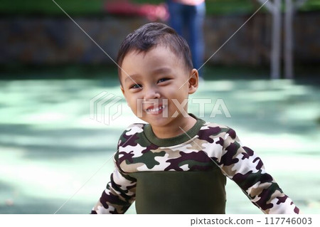 Asian boy about two years old wear a Military pattern shirt was standing smiling happily. 117746003