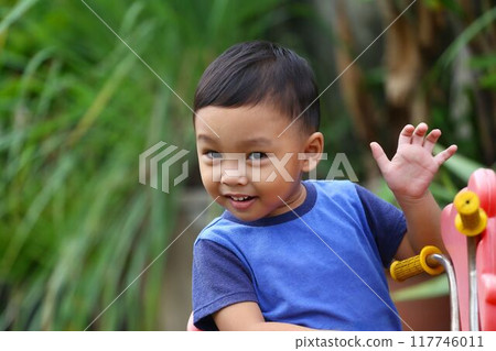 Asian boy about two years old wear a blue shirt was sitting on his toy car. 117746011