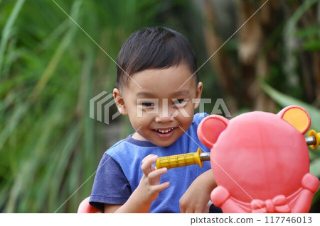 Asian boy about two years old wear a blue shirt was sitting on his toy car. 117746013