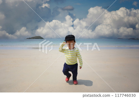 A boy about two years old wearing a long-sleeved shirt, walking on the beach smiling happily. 117746030