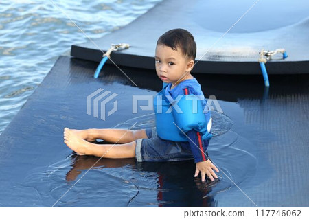 Asian boy about two years old wearing a life jacket and sitting on a raft in the middle of the sea, looking for his mother. Asian boy about two years old wearing a life jacket and sitting on a raft in the middle of the sea, looking for his mother. 117746062