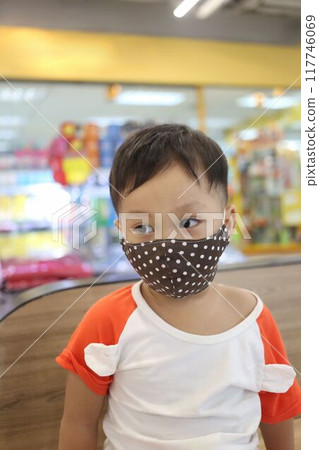 An Asian boy about two years old wears a mask when he goes to a shopping mall. 117746069