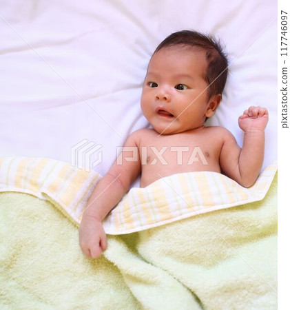 A infant boy lies on back and looking shocked, on a white mattress. A infant boy lies on back and looking shocked, on a white mattress. 117746097