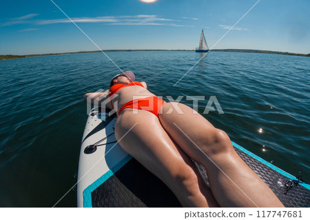 Woman Relaxing on Paddleboard in Summer 117747681