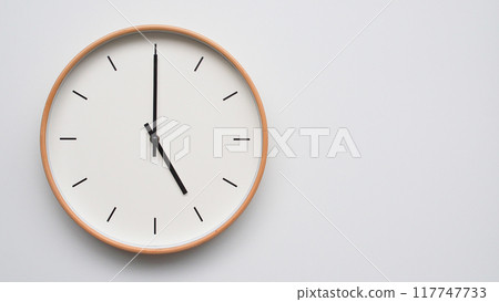 Minimalist wooden Wall Clock on White Wooden Surface with Space for Text. Time Set at 17.00/05.00 117747733