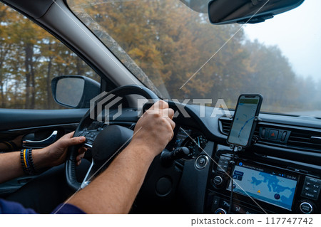 Person Driving by the road at foggy autumn highway Person Driving by the road at foggy autumn highway 117747742