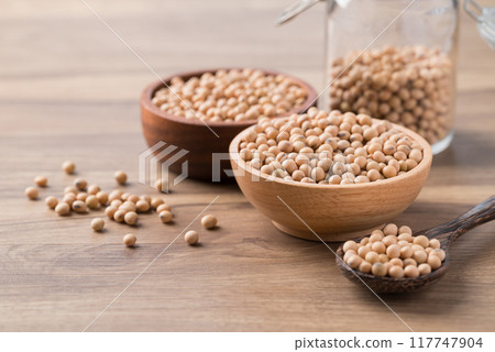 Soy bean seeds in wooden bowl, glass jar and spoon on wooden background Soy bean seeds in wooden bowl, glass jar and spoon on wooden background 117747904