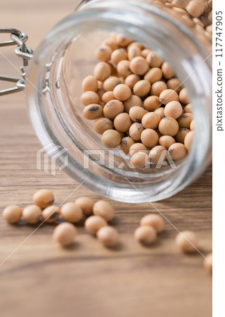 Soy bean seeds in glass jar on wooden background Soy bean seeds in glass jar on wooden background 117747905