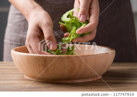 Sliced bitter gourd in bowl with hand prepare for cooking 117747919