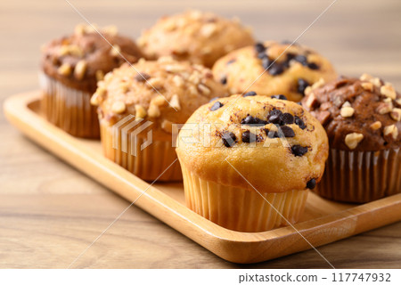 Vanilla chocolate chips muffin and chocolate almond muffin on wooden plate 117747932