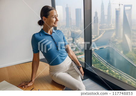 A meticulous and professional individual working in a modern office featuring a stunning city view 117748853