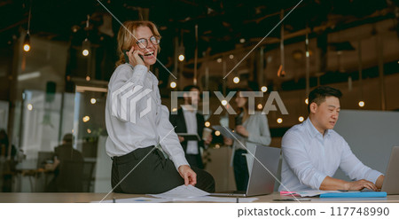 A Busy Professional Team Collaboratively Working Together in a Modern Office Environment 117748990