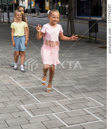 Funny children play hopscotch on the sidewalk in the city Funny children play hopscotch on the sidewalk in the city 117749297