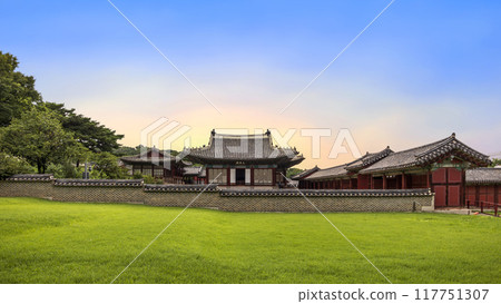 Red wooden buildings surrounding Changgyeonggung Palace, showcasing traditional Korean architecture, beautifully contrast with the green grass on the grounds. 117751307