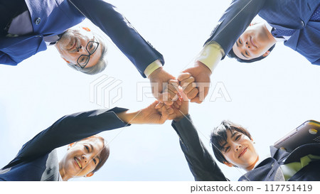 A group of business people of all ages fist bumping each other A group of business people of all ages fist bumping each other 117751419
