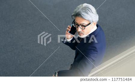 Executive man talking on smartphone in lobby 117751484