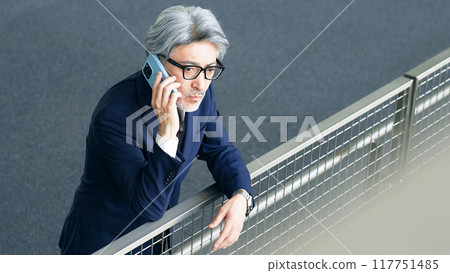 Executive man talking on smartphone in lobby Executive man talking on smartphone in lobby 117751485