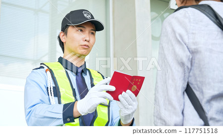 Security guard checking passports 117751518