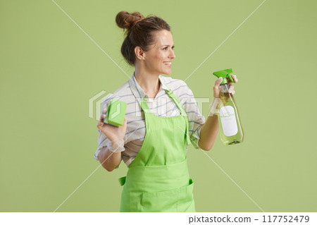 smiling woman in green apron and rubber gloves on green smiling woman in green apron and rubber gloves on green 117752479