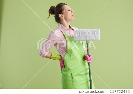 sad woman in green apron and rubber gloves against green sad woman in green apron and rubber gloves against green 117752483