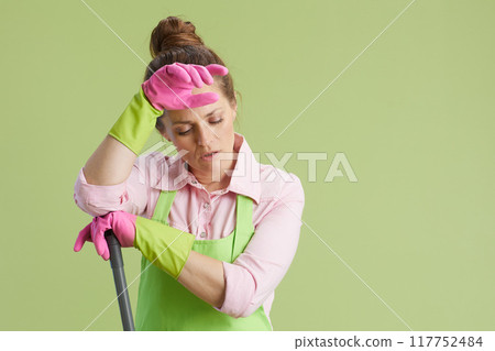 sad woman in green apron and rubber gloves on green sad woman in green apron and rubber gloves on green 117752484