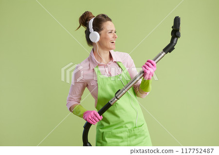 smiling 40 years old woman vacuum cleaner isolated on green smiling 40 years old woman vacuum cleaner isolated on green 117752487
