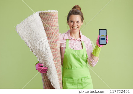 happy woman showing smartphone screen isolated on green 117752491