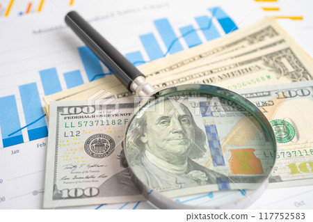 Magnifying glass with US dollar banknotes on graph. Finance business and trading. 117752583