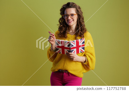 smiling fit woman in sweater and glasses against green 117752788